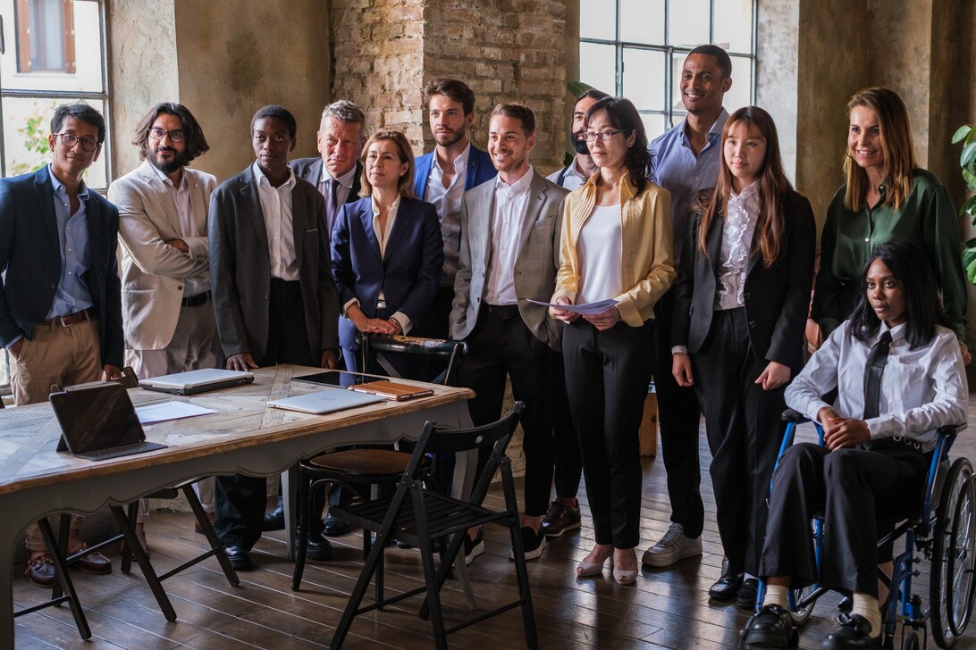 A diverse startup team in formal attire gathered around a table in a modern office, symbolizing strategic planning for profit and profitability.